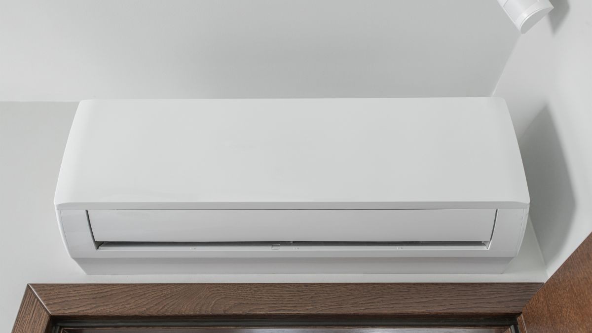 Witte airco binnenunit boven een houten deur in een woning, met een strak ontwerp dat past bij moderne airco merken.